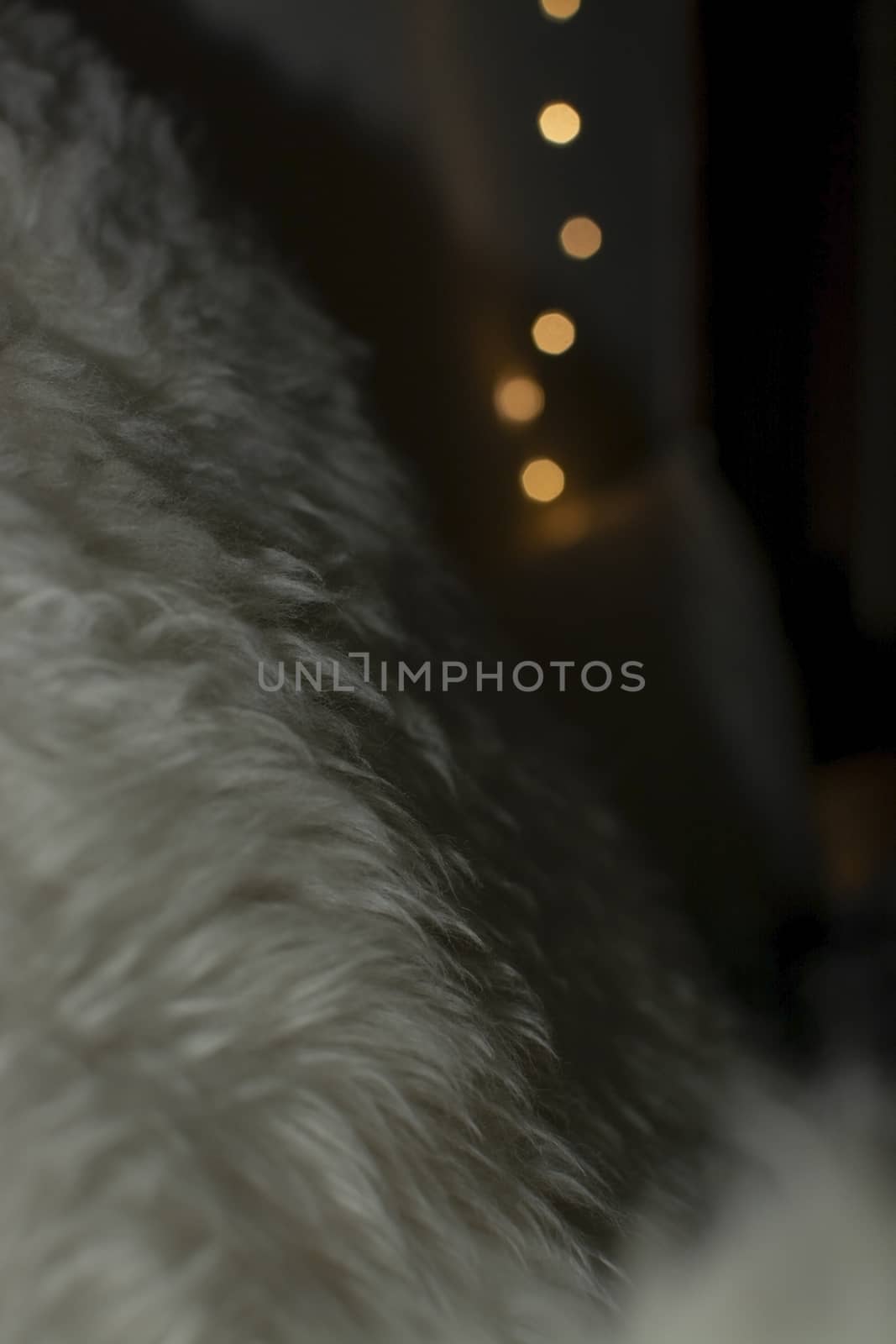 White lambswool fur and bokeh christmas lights winter concept background texture.