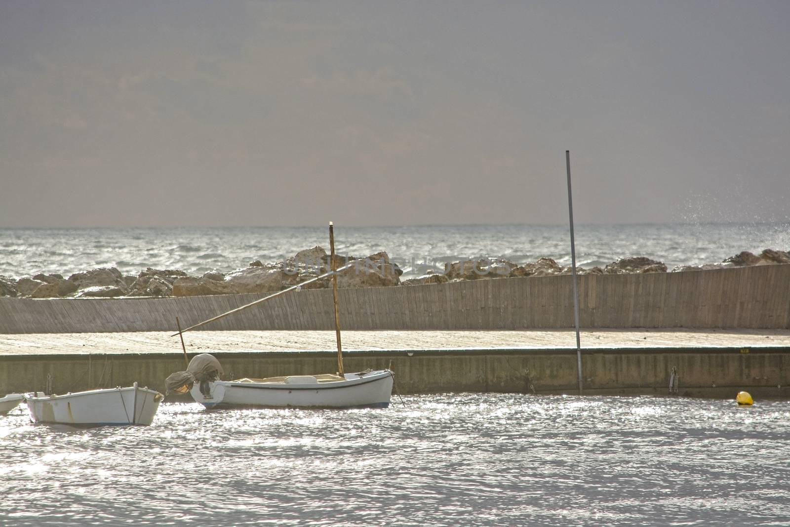 Mediterranean sea view with pier against dark skies with dramatic light on a winter day in Mallorca, Spain.