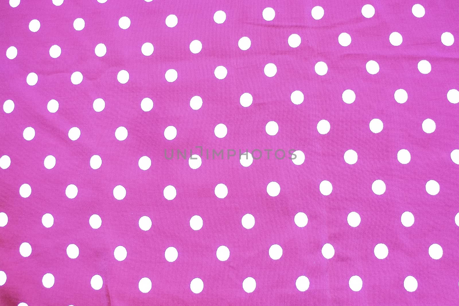Pink and white polka dot printed fabric fun romantic background texture.