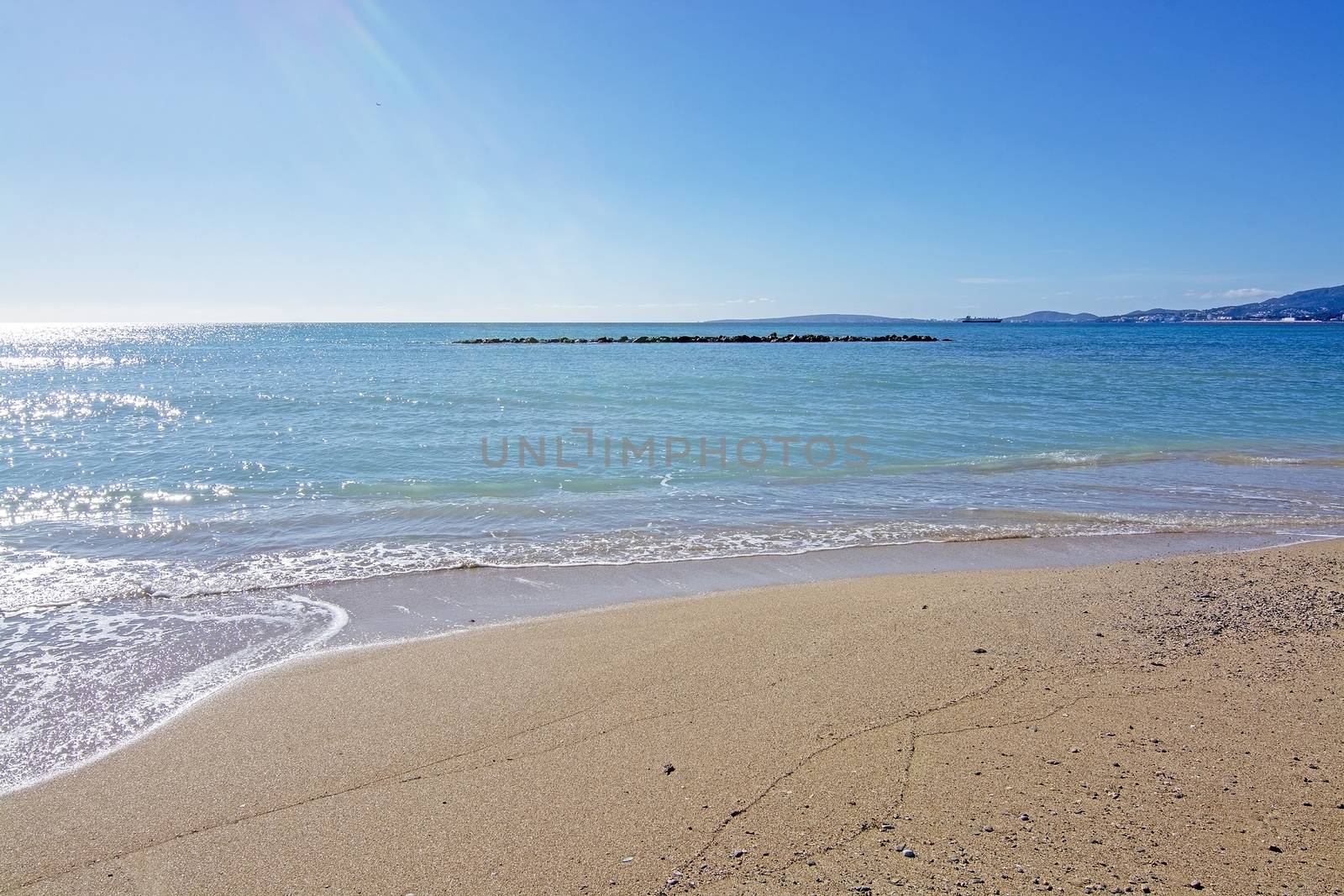 Untouched sand beach with wave residue pattern and blue sea in Mallorca, Spain.