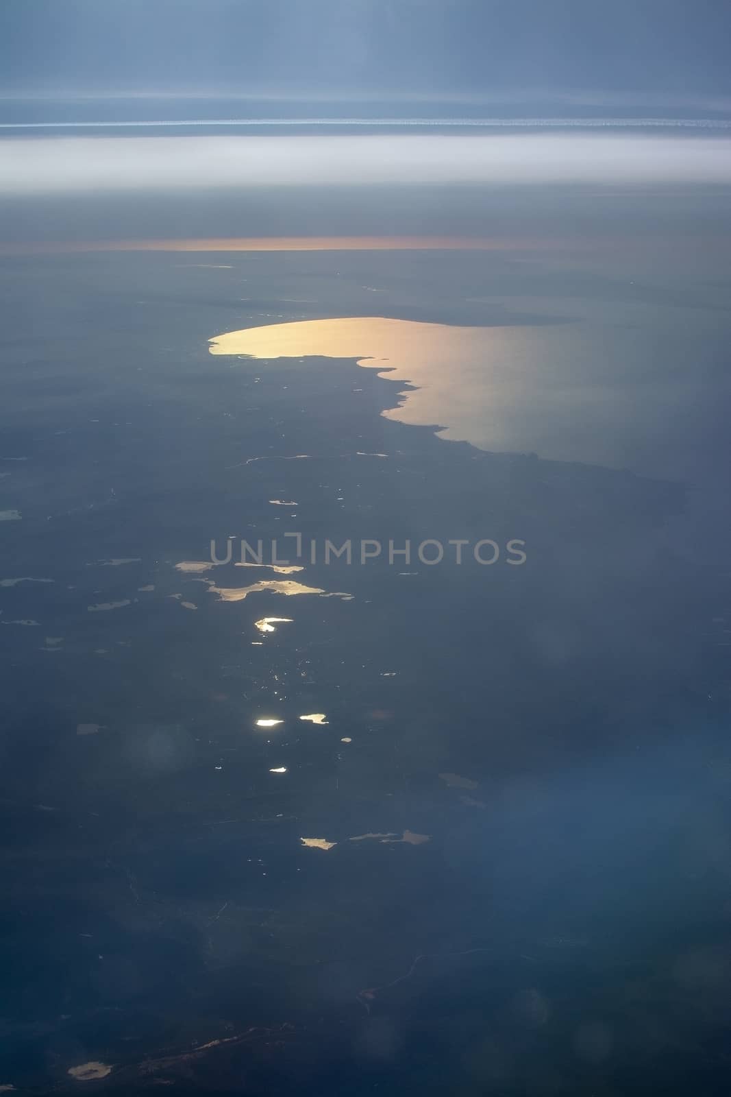 Aerial landscape with golden light over bay of water and forest in southwestern Sweden