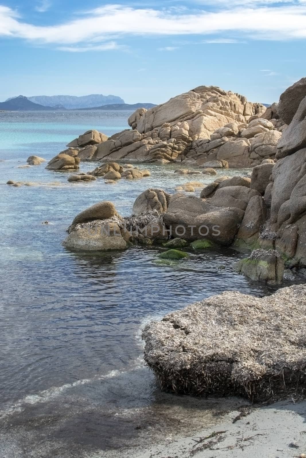 Green water and granite boulders on a beach in Costa Smeralda, Sardinia, Italy, vertical image.