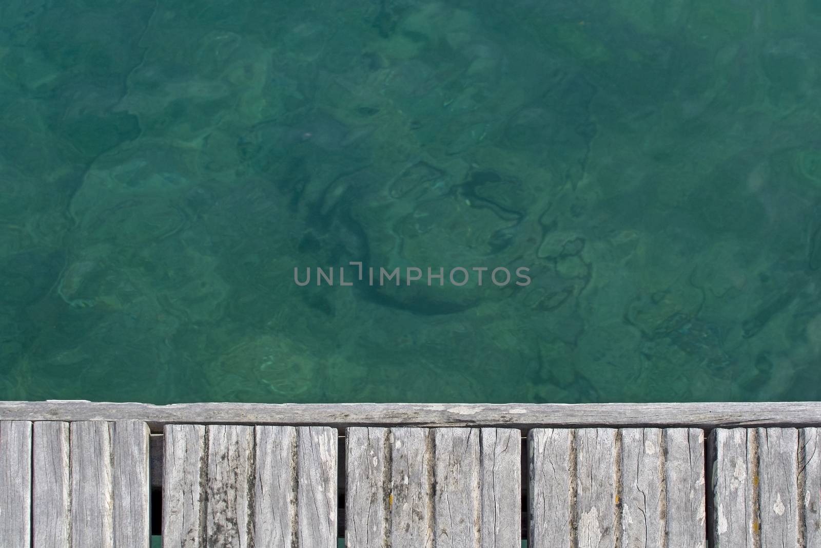 Emerald green water and wood boardwalk background texture, Sardinia, Italy.