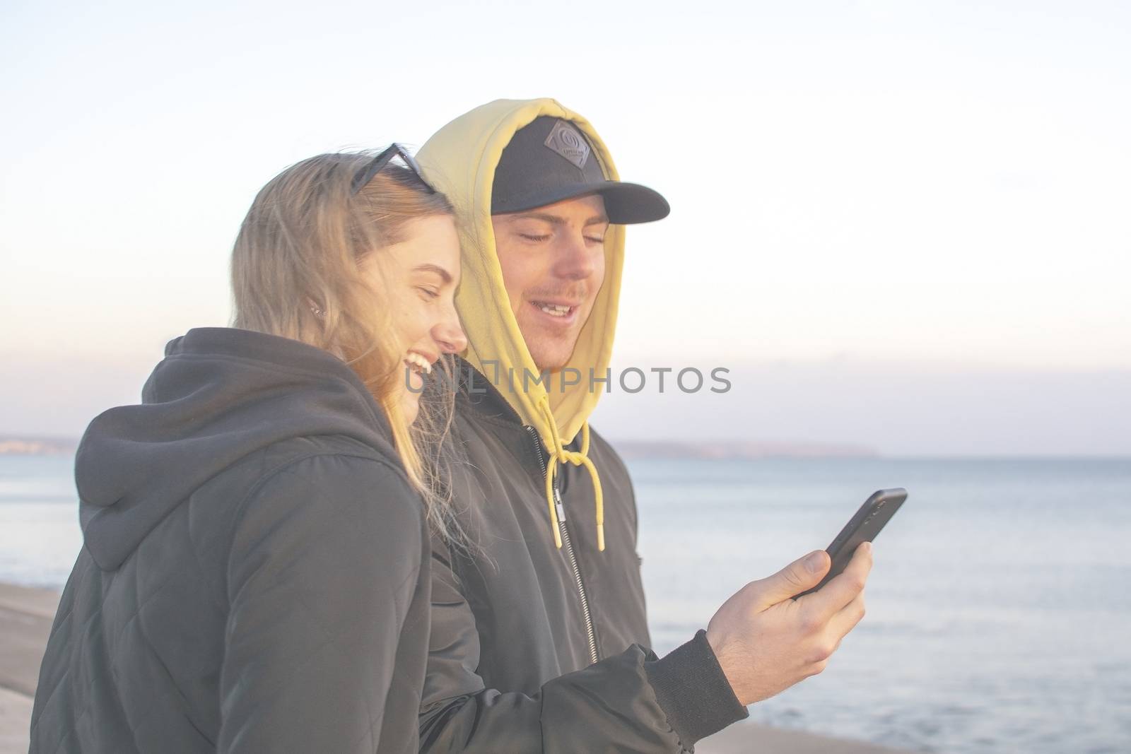 Handsome young natural and casual looking couple with smartphone by ArtesiaWells