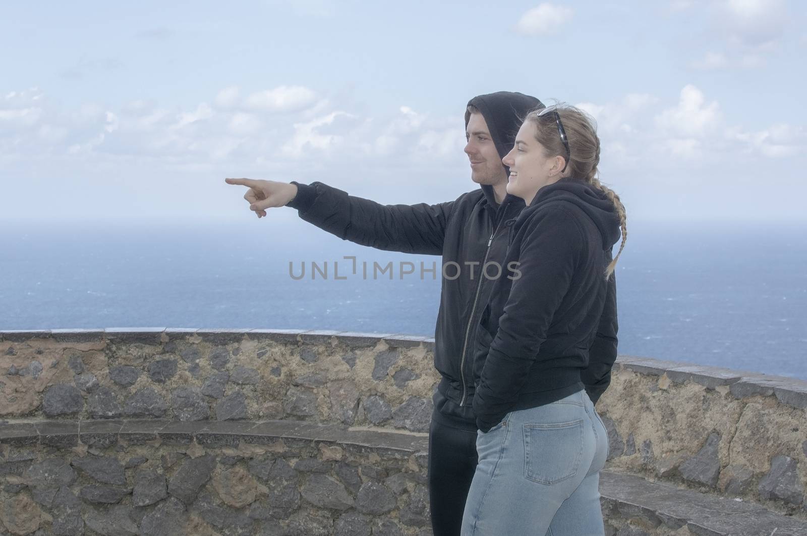 Young beautiful casually dressed couple stand high up watching o by ArtesiaWells