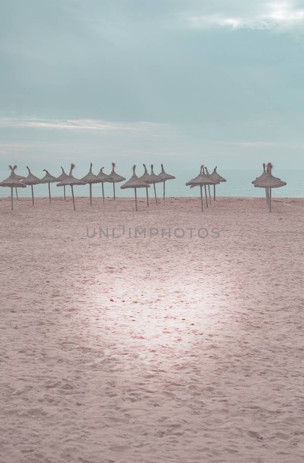 Beautiful sand beach and straw parasols toned in Living Coral by ArtesiaWells