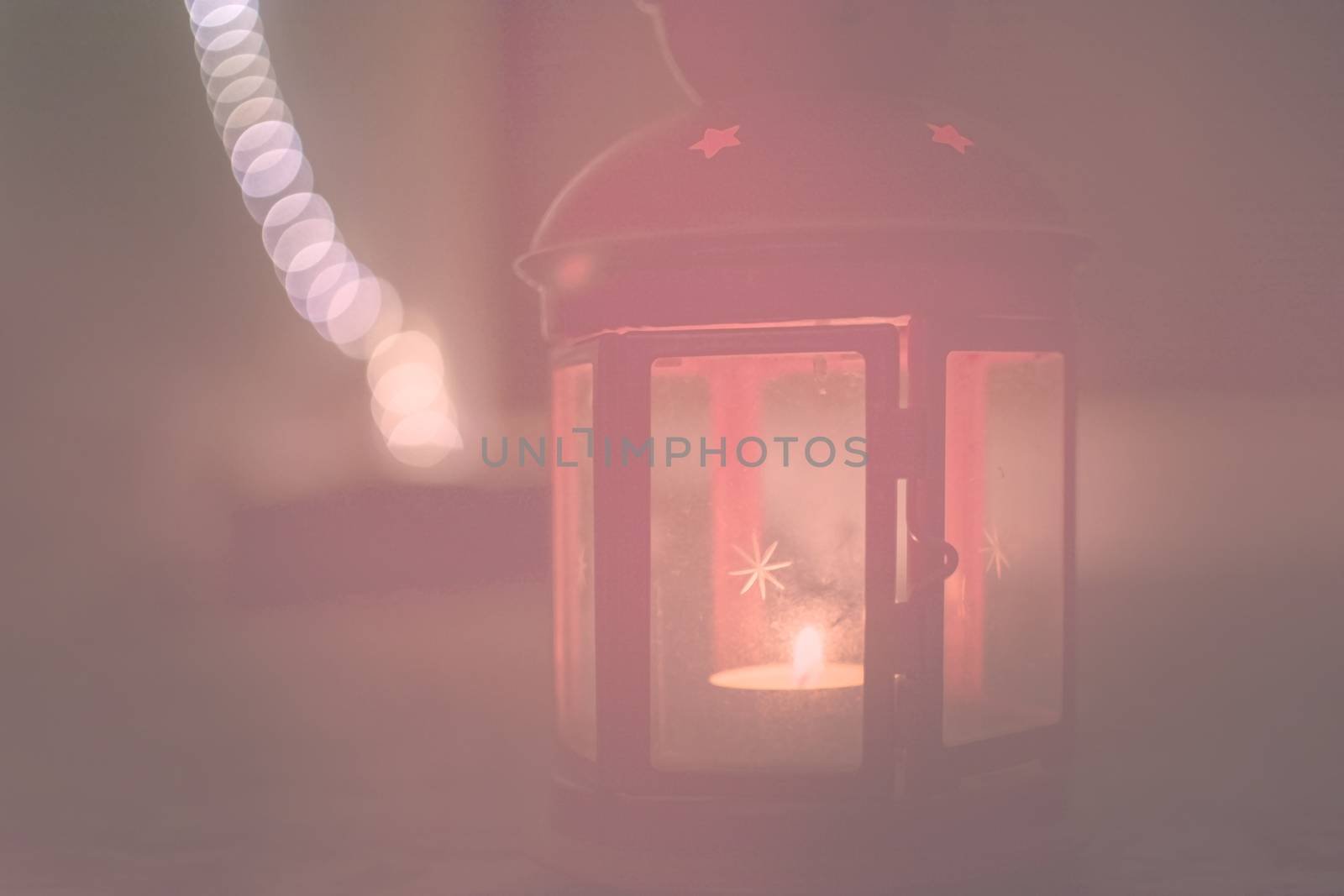 Red lantern with star on glass and burning tealight in darkness toned in hazy Living Coral warm red shades