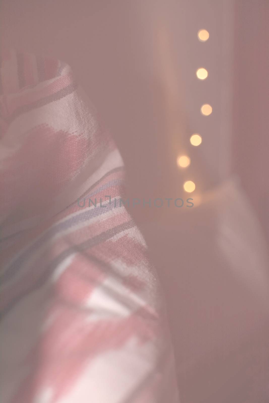 Vertical closeup of traditional Majorca red ikat fabric and bokeh light string toned in Living Coral shades