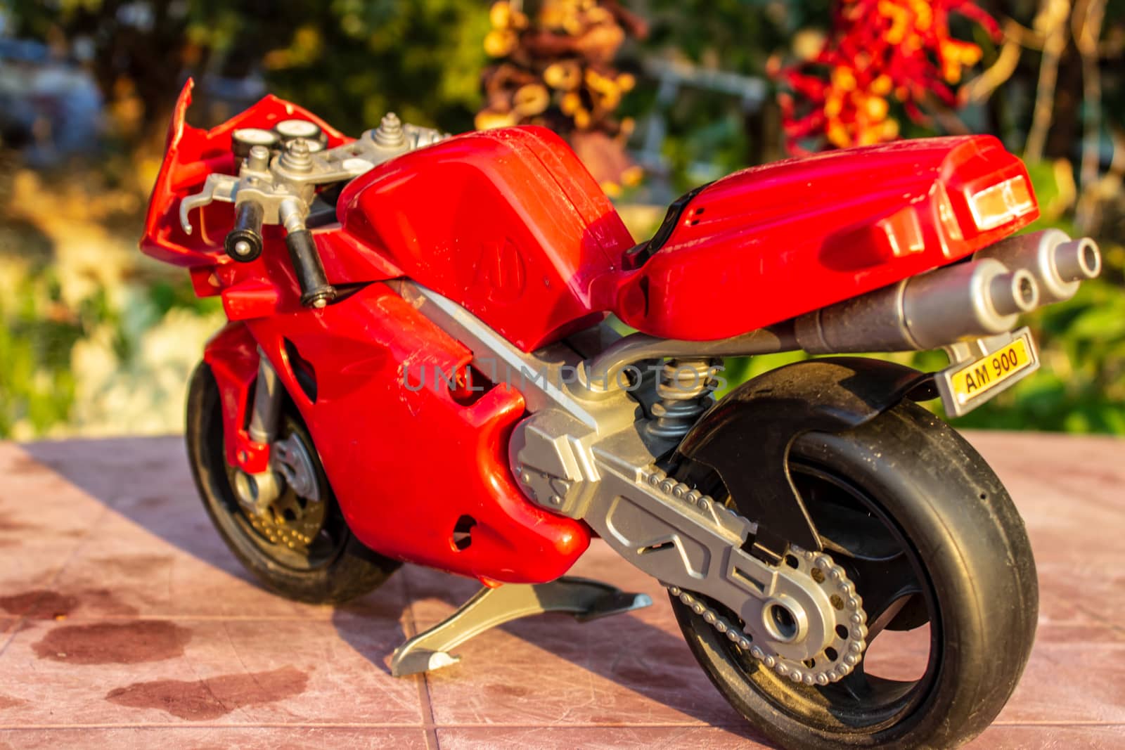 a isolated closeup red toy motorcycle with warm colors. photo has taken from a garden.