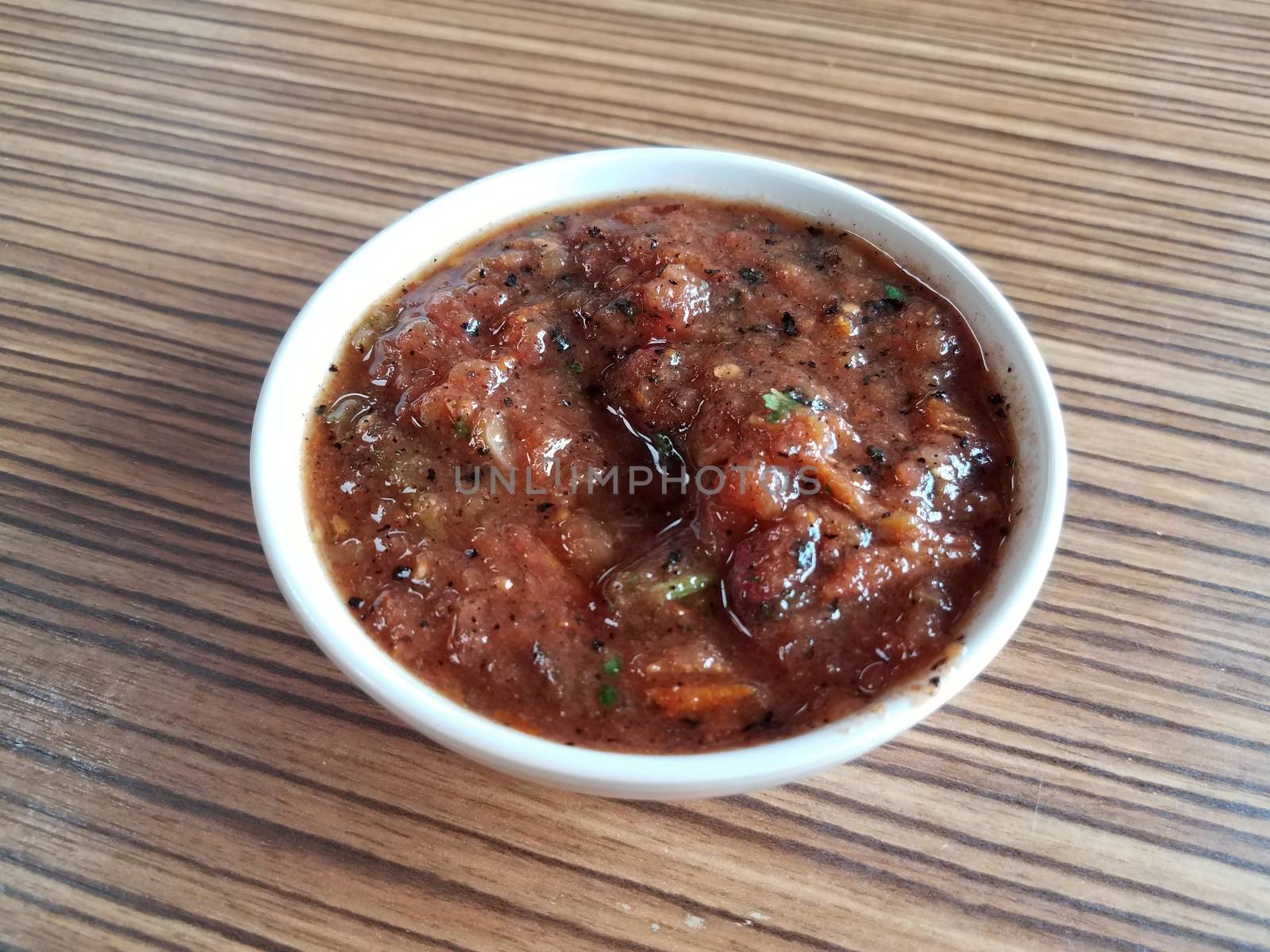 spicy salsa with tomato and pepper and other seasoning on brown wood table