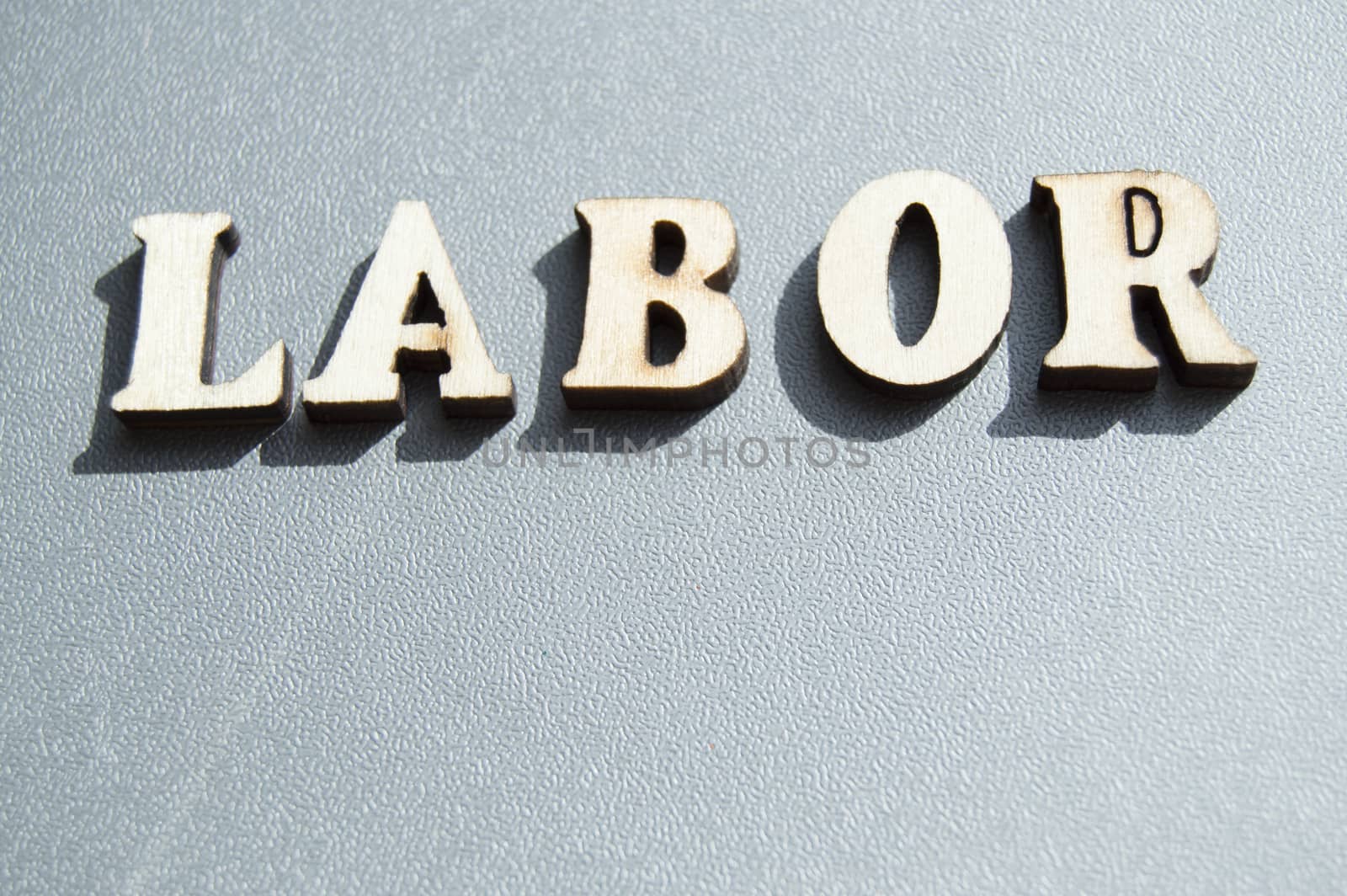 The word work written with wooden letters on a gray background, the sunlight, ready for the layout design, the concept of the holiday labor Day.