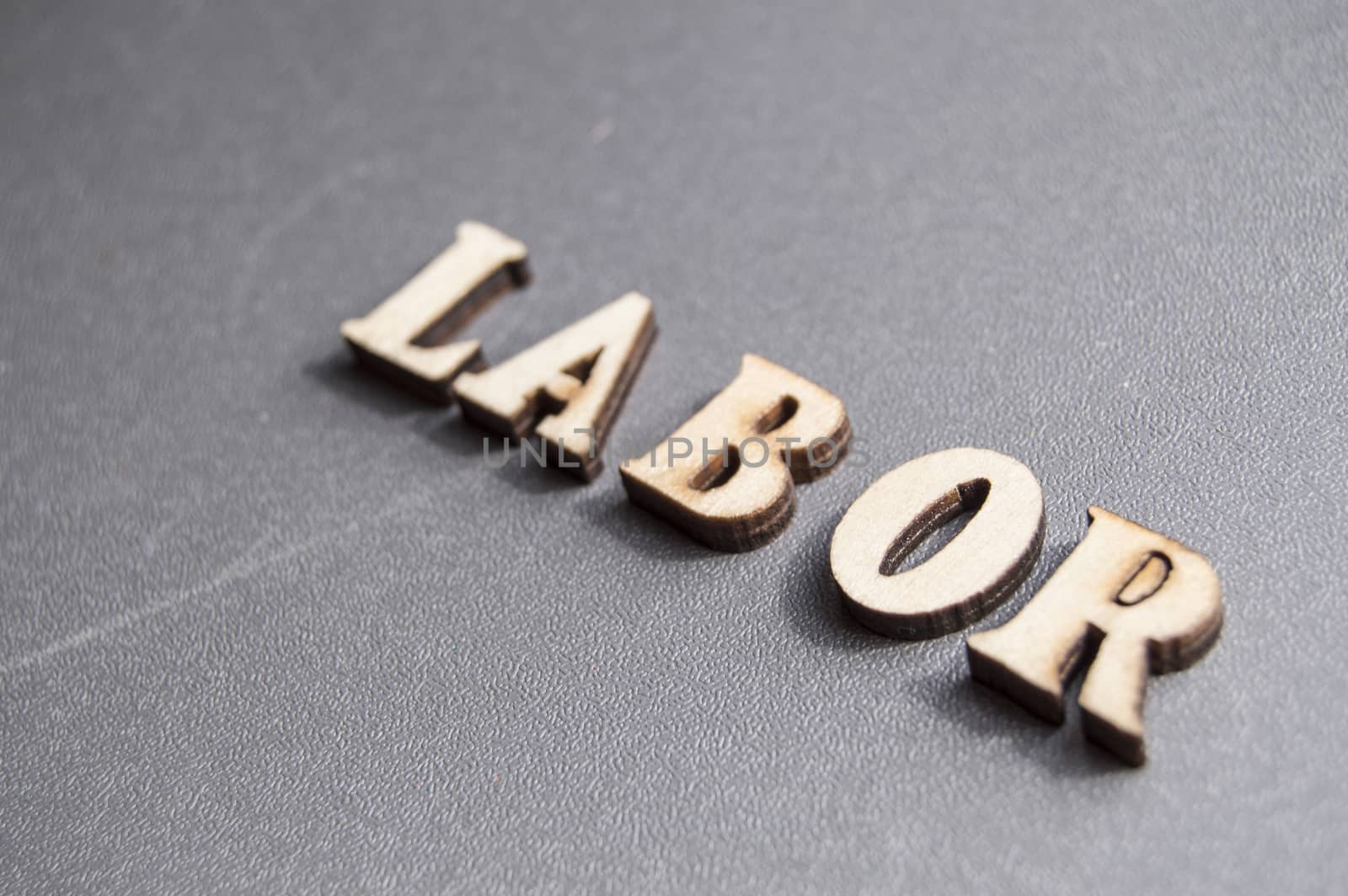 The word work written with wooden letters on a gray background, the sunlight, ready for the layout design, the concept of the holiday labor Day.