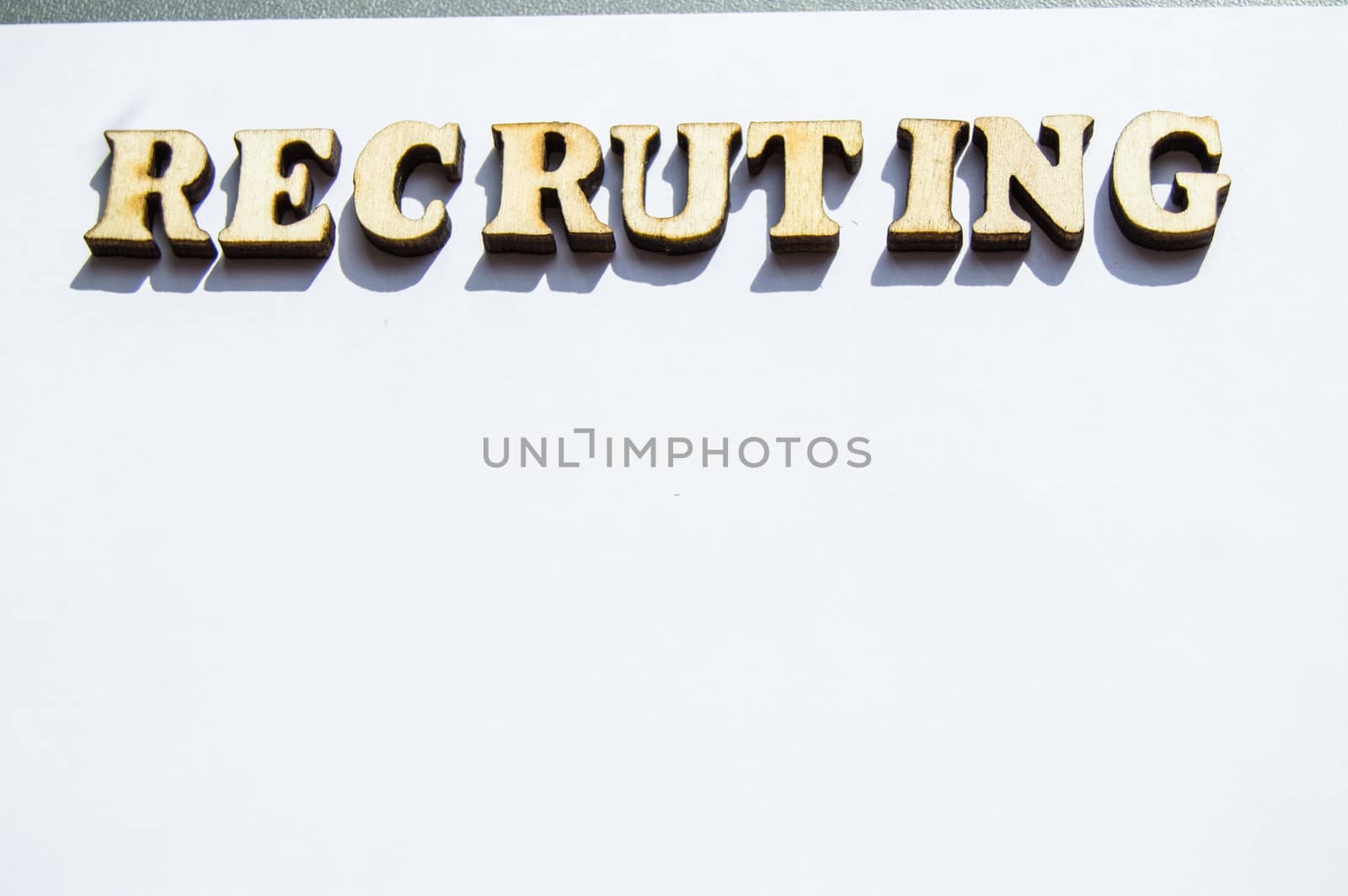 The word recruiting is written in wooden letters on a white background, the concept of hiring employees, recruitment in business and army.