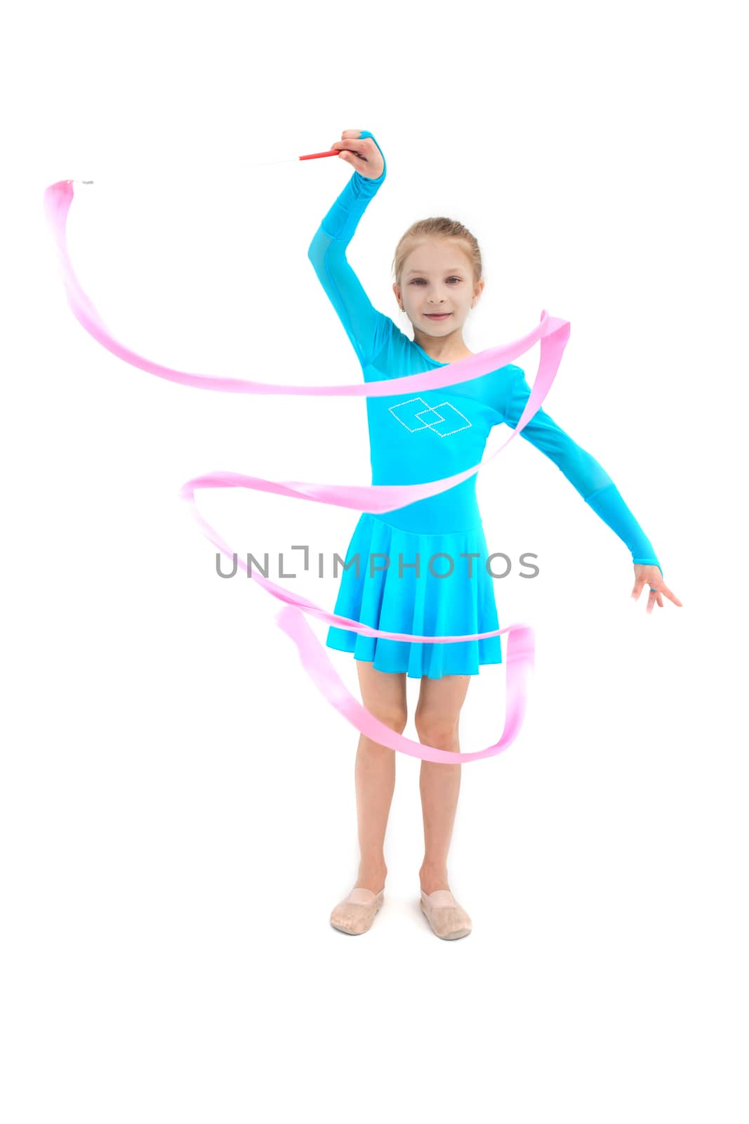 Young girl gymnast exercising with pink ribbon on white studio background