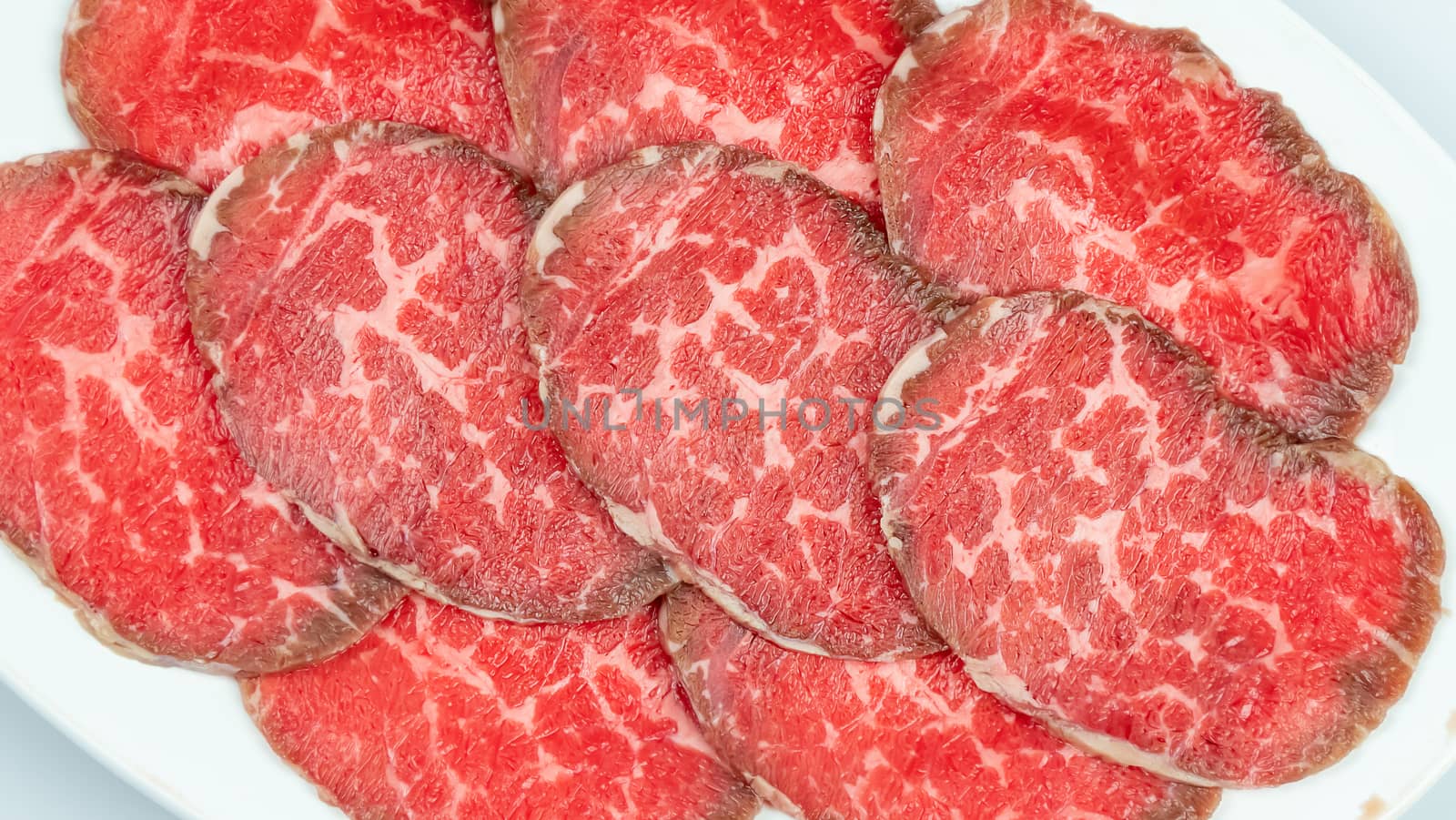 Top view of some raw beef on a plate over white background