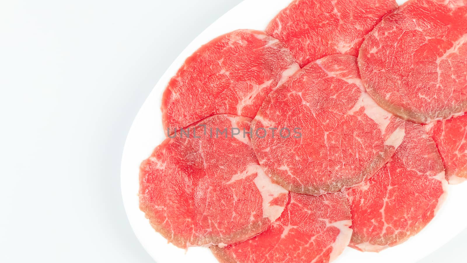 Top view of some raw beef on a plate over white background