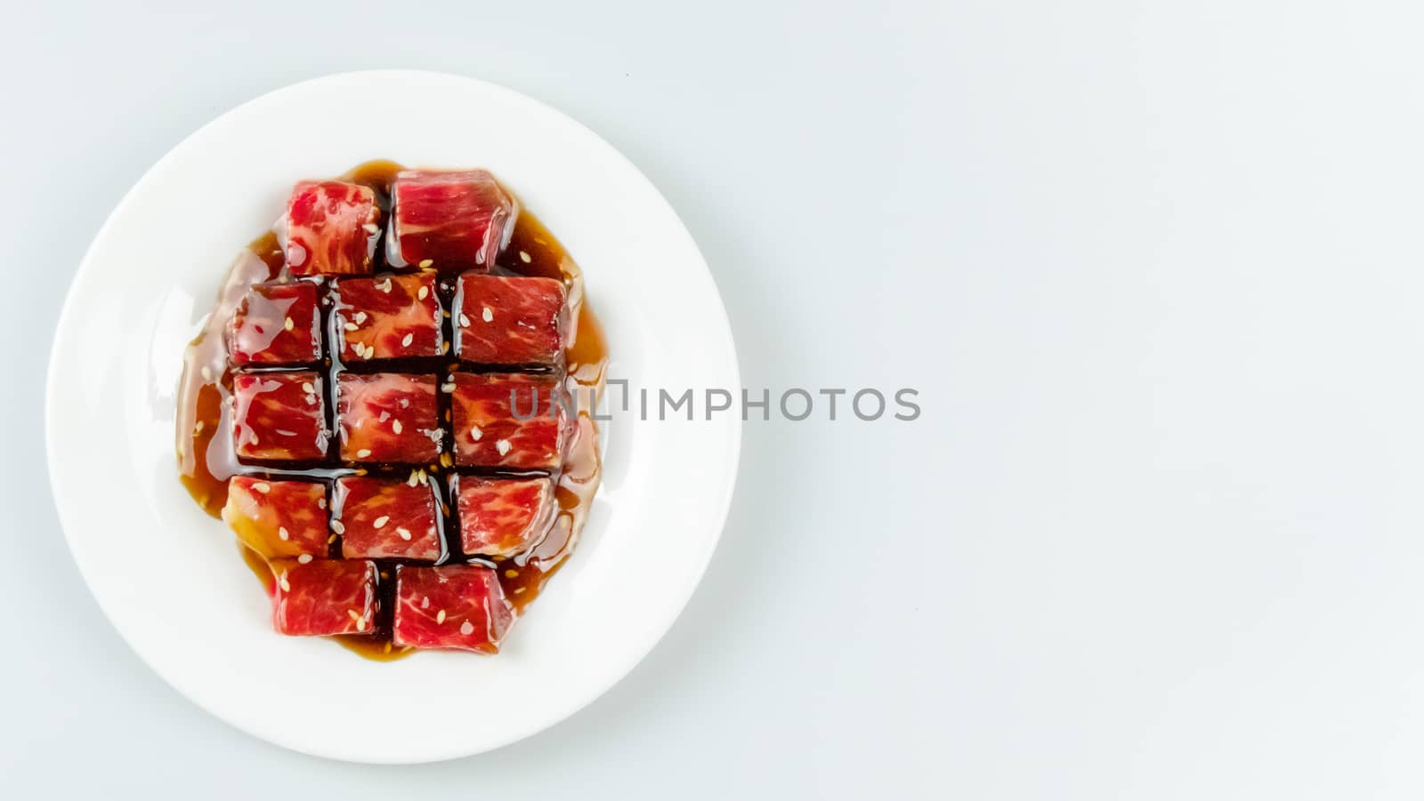 Top view of some raw beef with sauce on a plate over white background