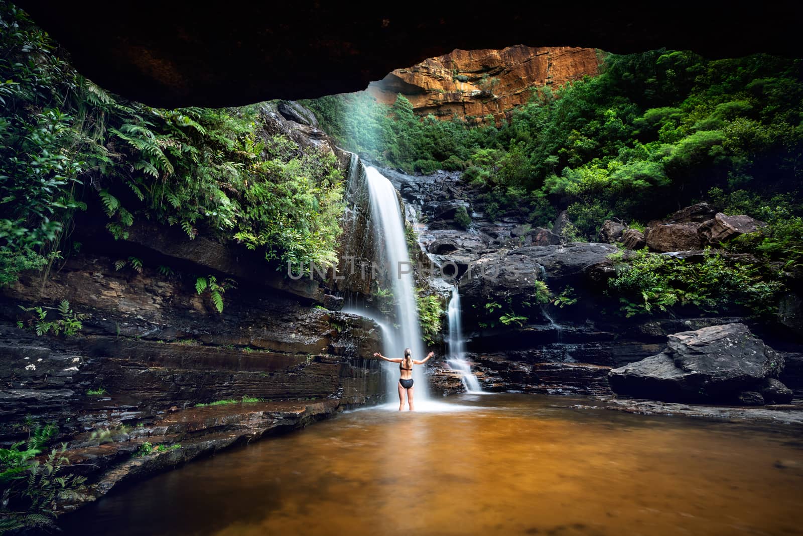 Woman cooling off in a mountain oasis and waterfall by lovleah