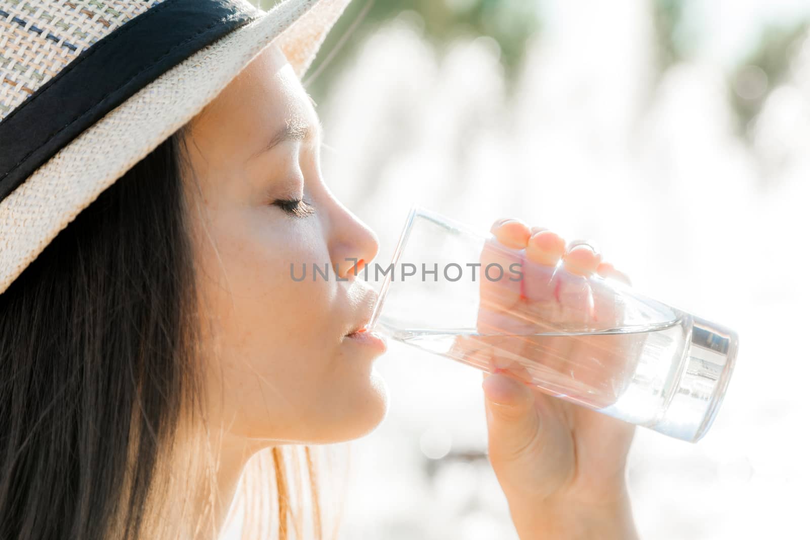 The beautiful girl in a hat drinks water in a glass