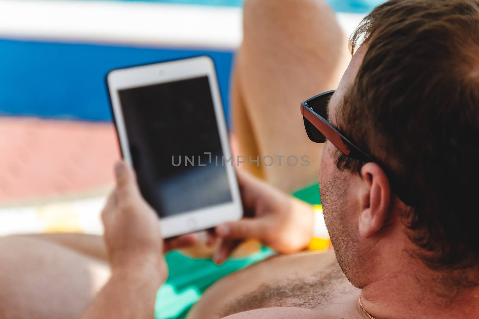 A young man in sunglasses holds a tablet in his hands. Freelance by Tanacha