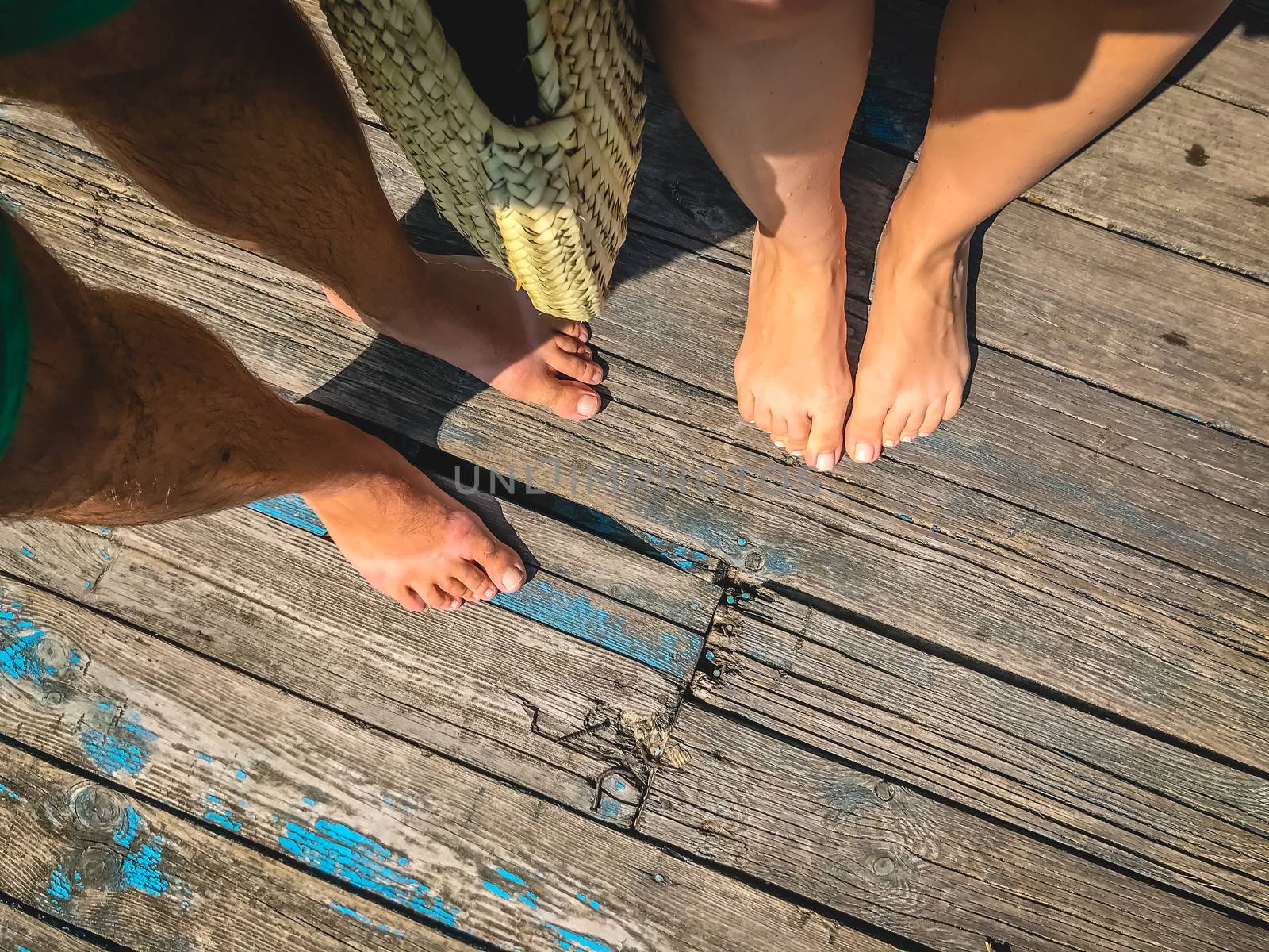 Top view, photo of a pair of bare feet on a wooden old floor. Photos on vacation, beach, summer.