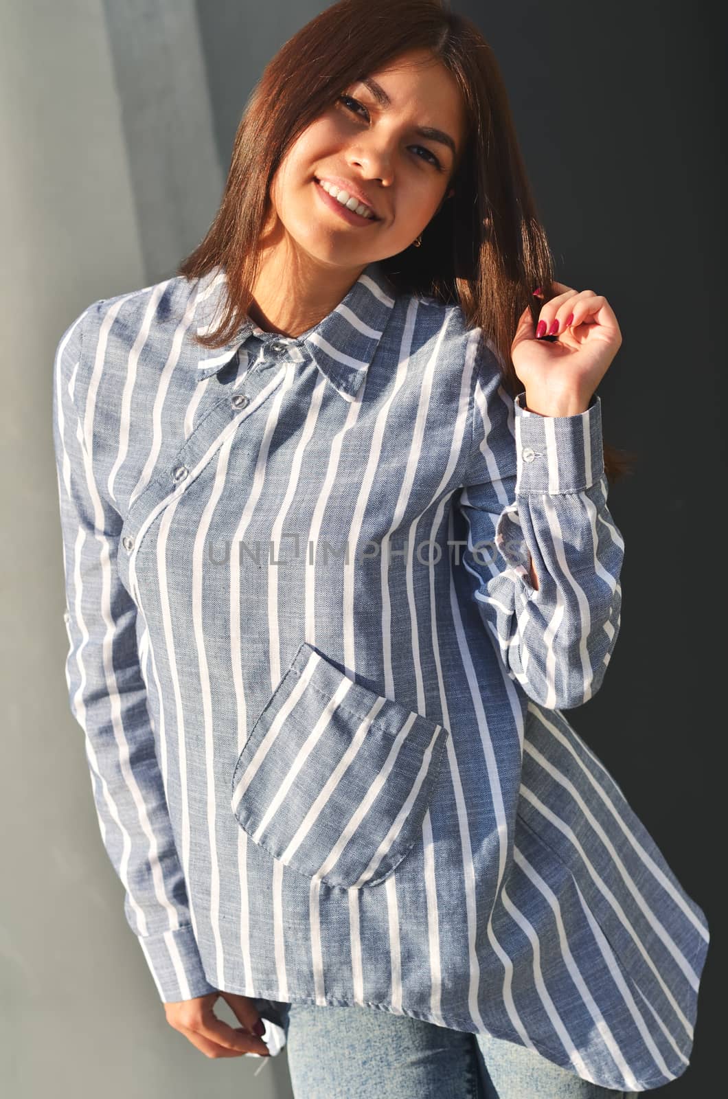 Portrait's young cool asian girl stands near the wall and posing and she dressed a striped shirt