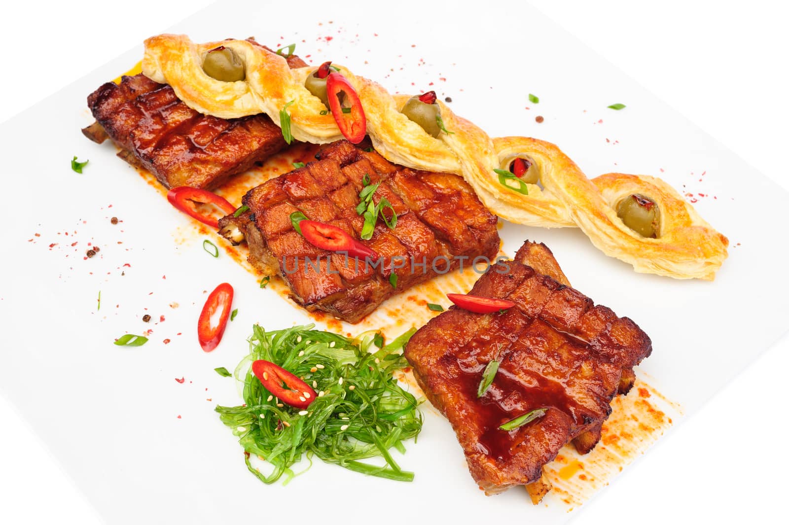 grilled pork ribs with bread pigtail and seaweed, served on plate, isolated on white
