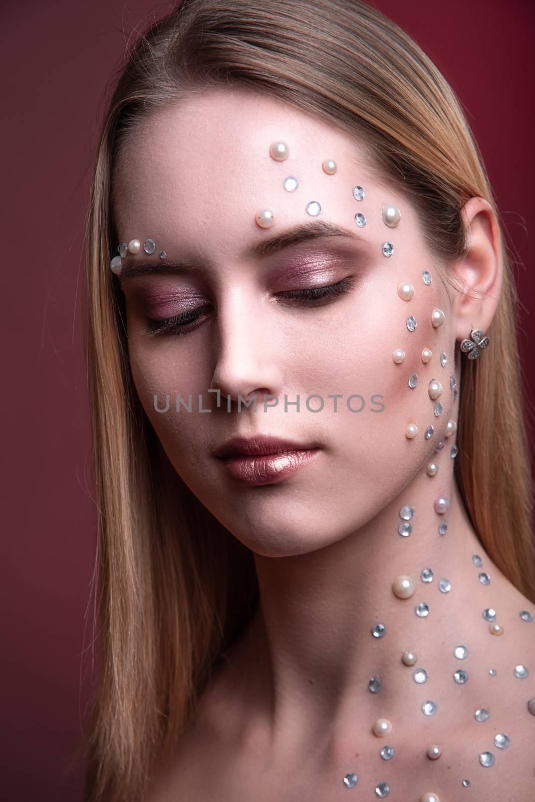 Portrait of a girl with original and creative makeup with white and pearl rhinestones