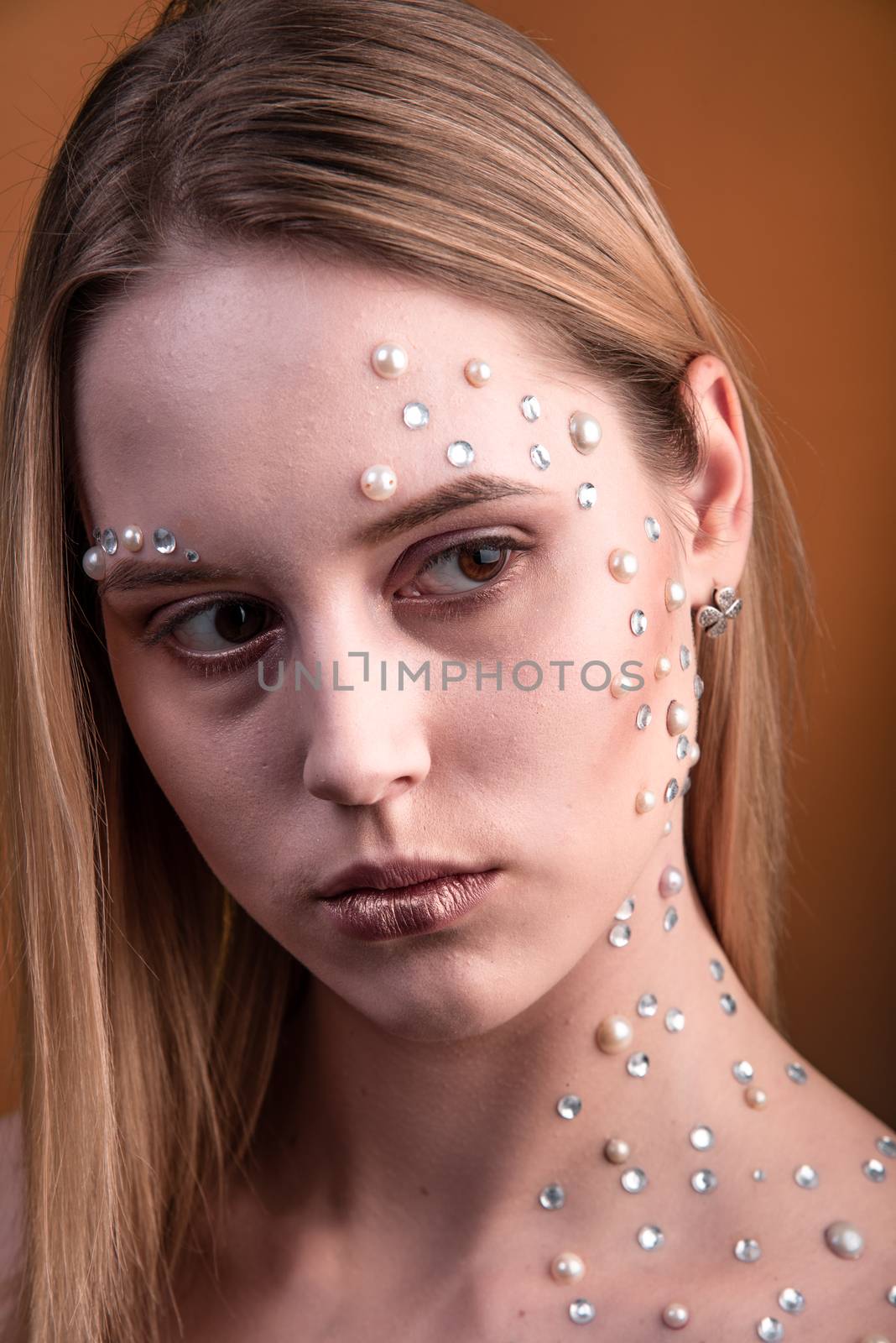 Portrait of a girl with original and creative makeup with white and pearl rhinestones