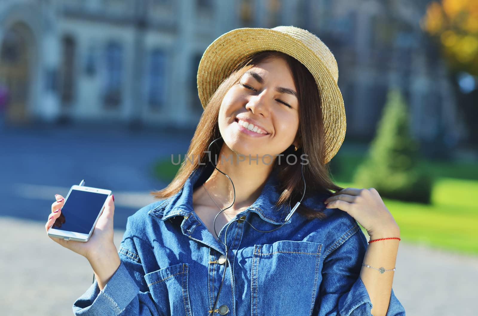 A young girl of Asian appearance enjoys life and listens to music raising her head up and smiling with her eyes closed