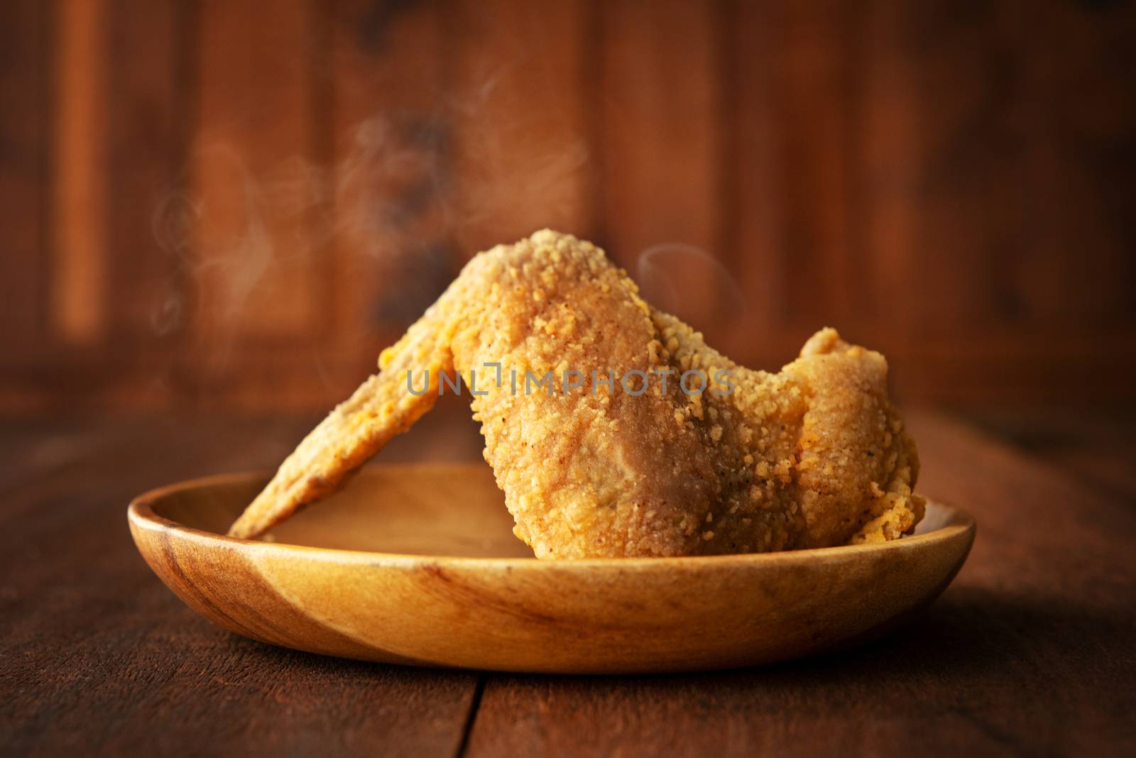 Plate of original recipe fried chicken wing, on dark wooden background.