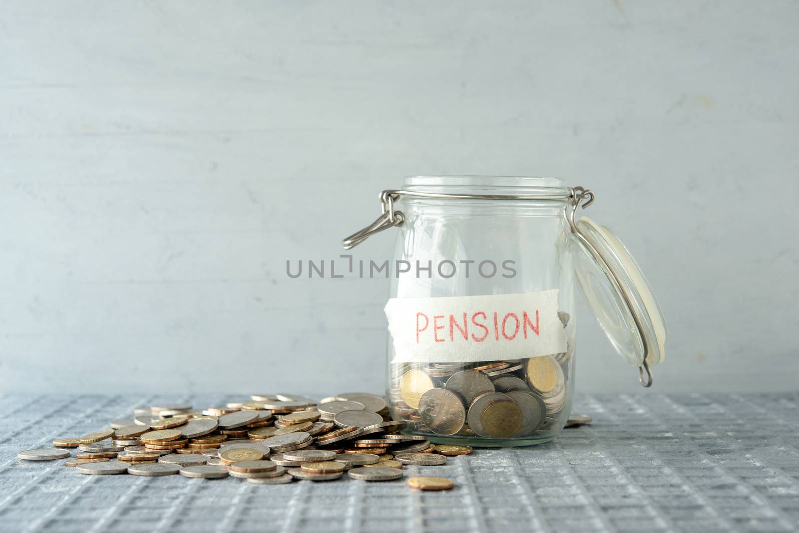 Coins in glass money jar with pension label, financial concept. 