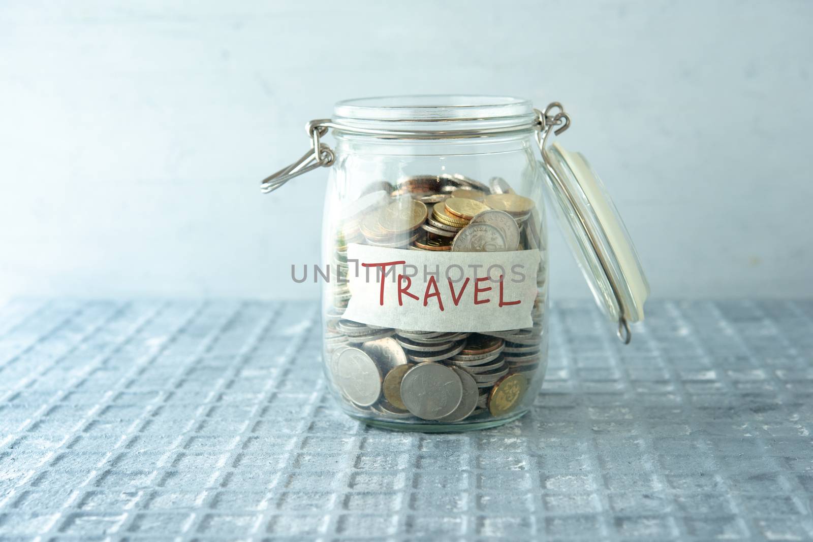 Coins in glass money jar with travel label, financial concept.
