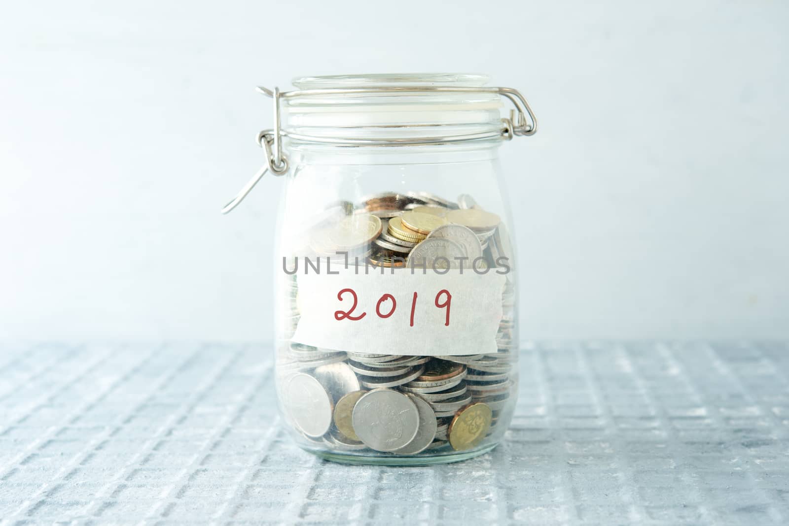 Coins in glass money jar with 2019 label, financial concept.