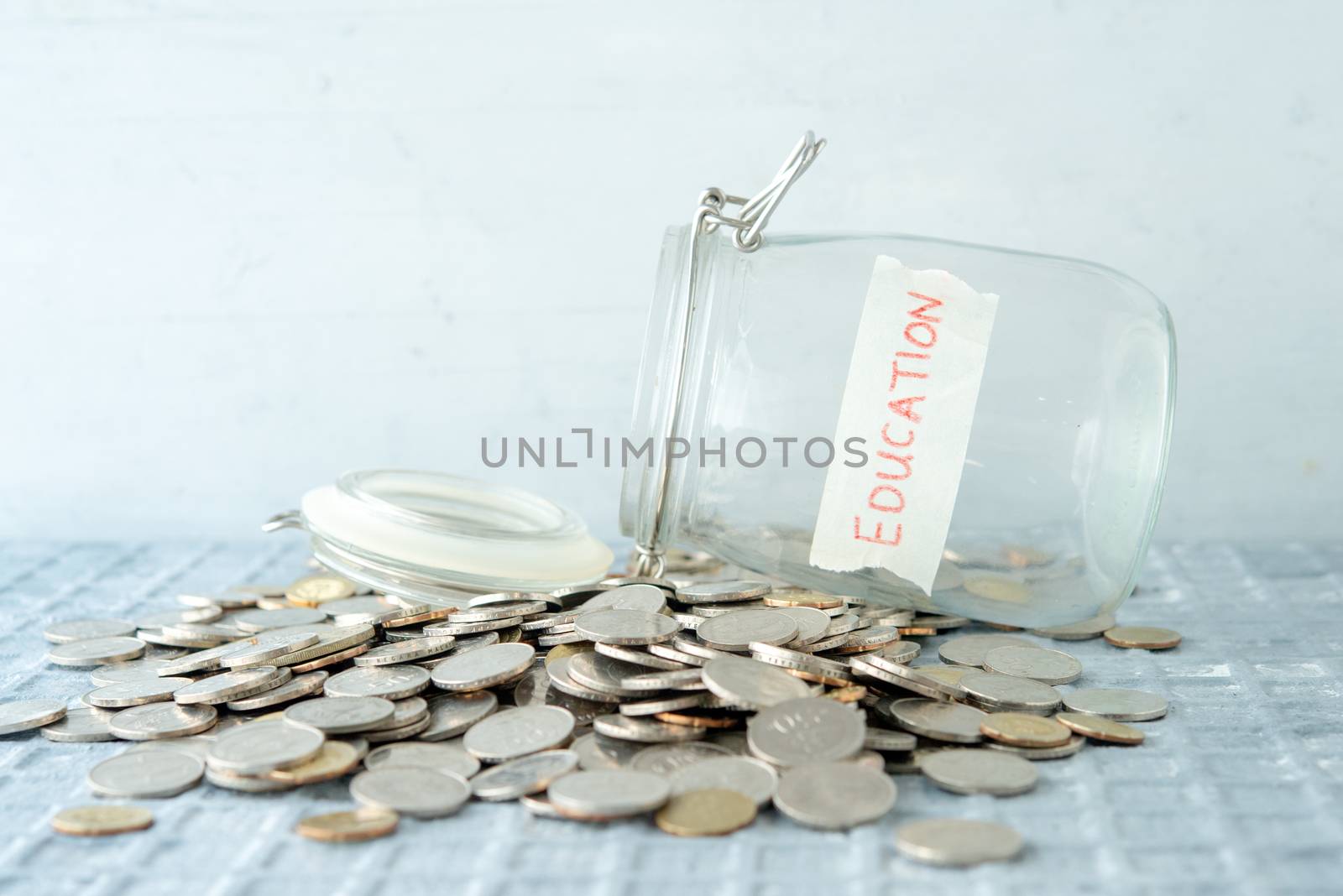 Coins and glass money jar with education label, financial concept.