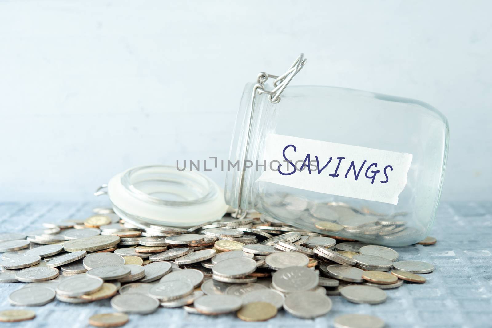 Coins and glass money jar with savings label, financial concept.