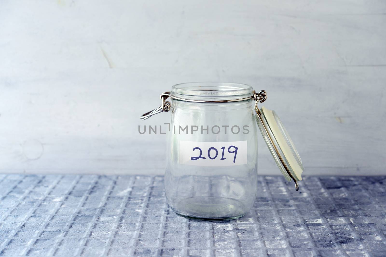 Empty glass money jar with 2019 label, financial concept.