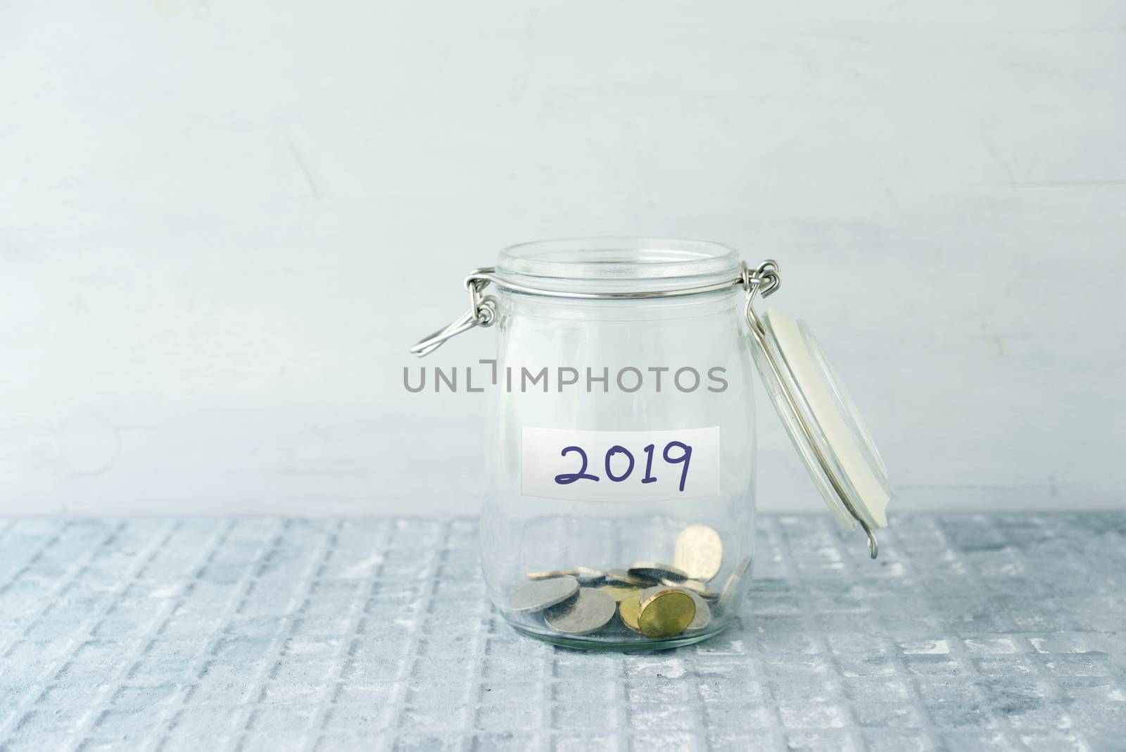 Empty glass money jar with 2019 label, financial concept.