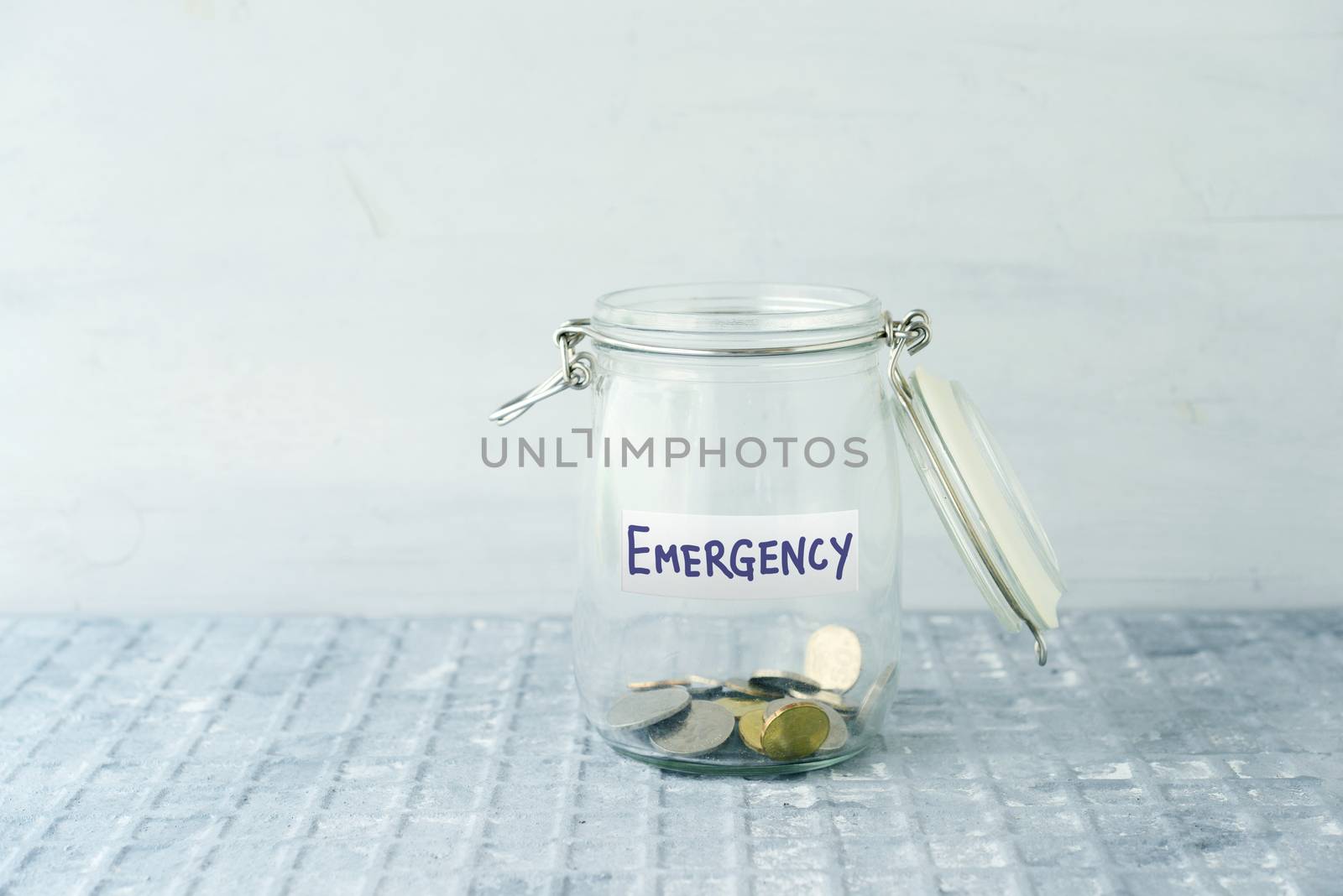 Coins in glass money jar with emergency label, financial concept.