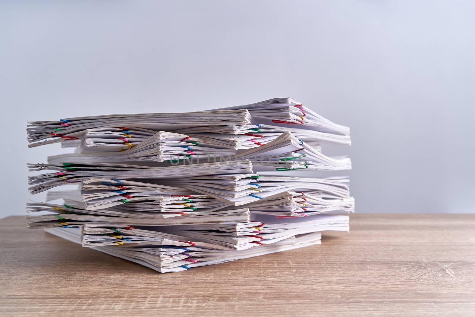 Close up pile overload document of report of sale with colorful paperclip place on wood table and white background with copy space. Business and finance concepts successful photography.