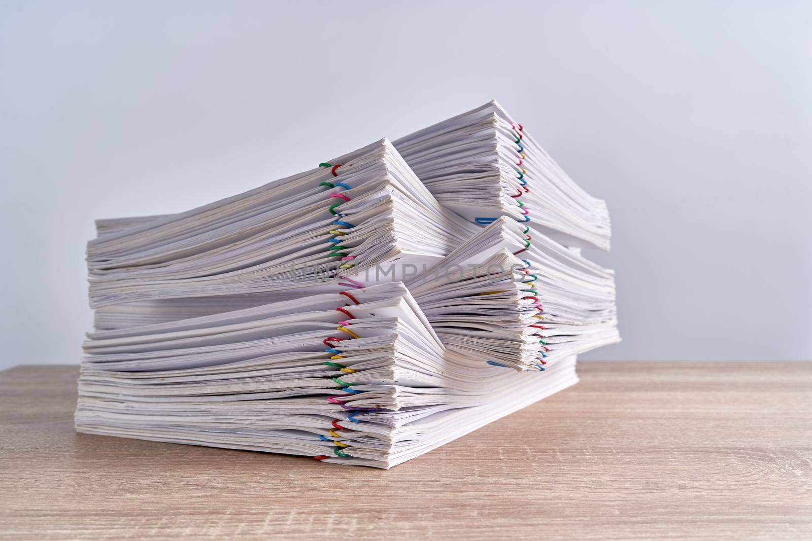 Close up pile overload paperwork of report of sale with colorful paperclip place on wood table and white background with copy space. Business and finance concepts successful photography.