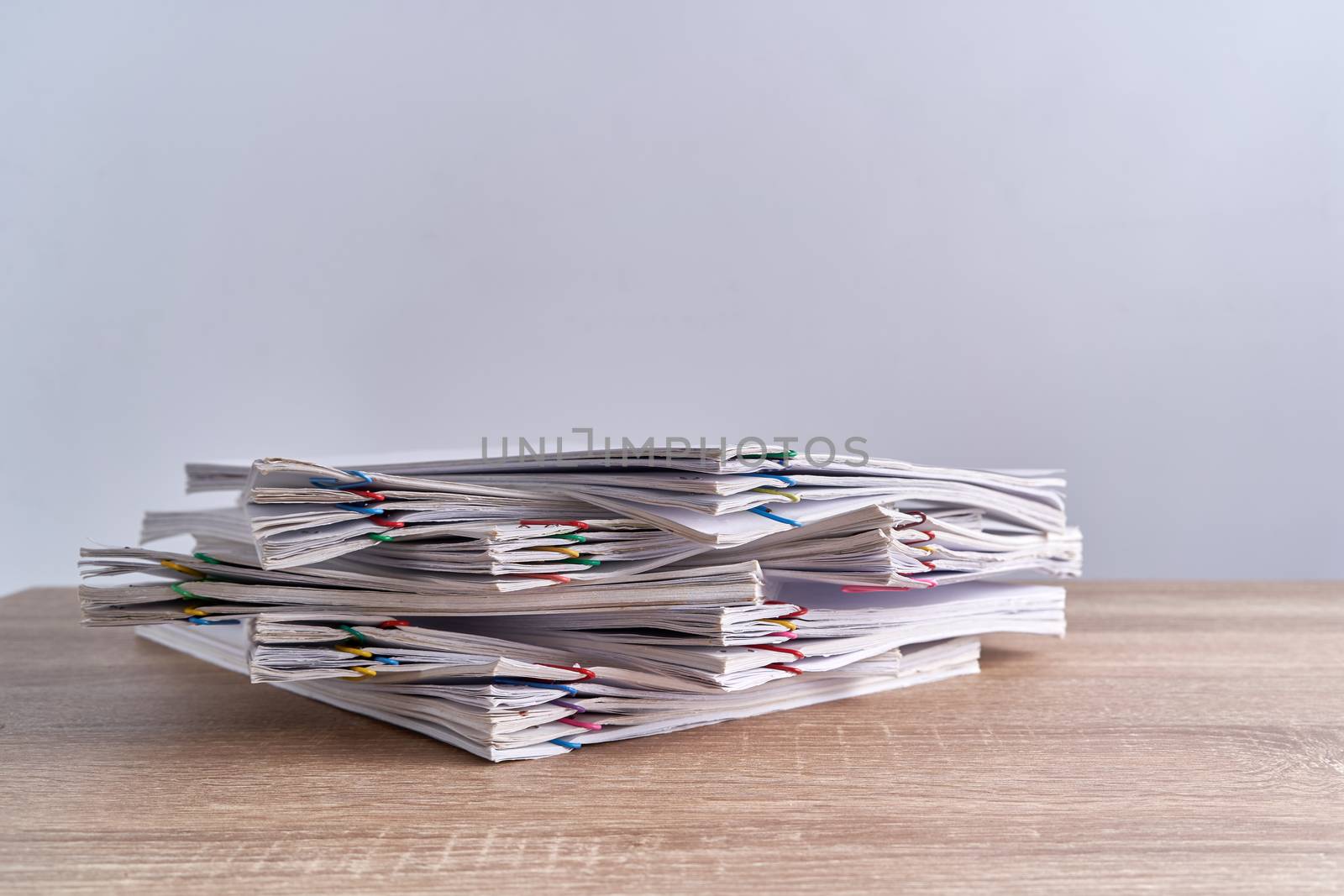 Pile overload document of report of receipt with colorful paperclip place on wood table and white background with copy space. Business and finance concepts successful photography.