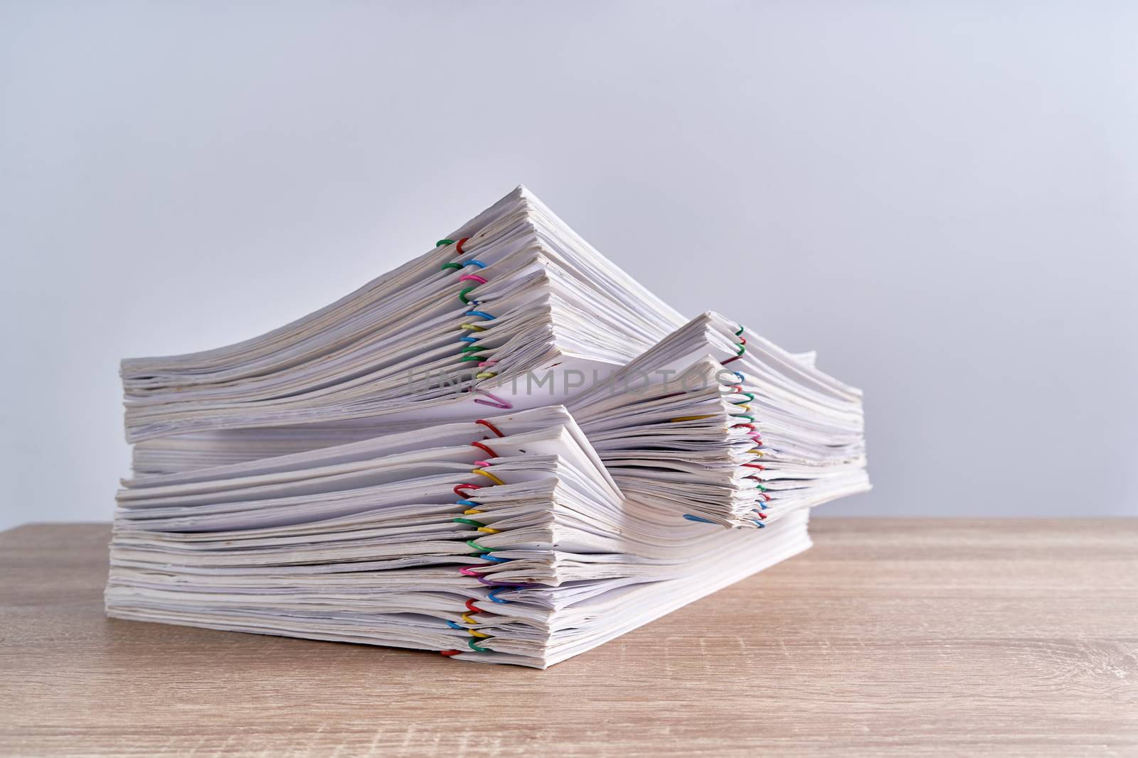 Pile overload paperwork of report of receipt with colorful paperclip place on wood table and white background with copy space. Business and finance concepts successful photography.