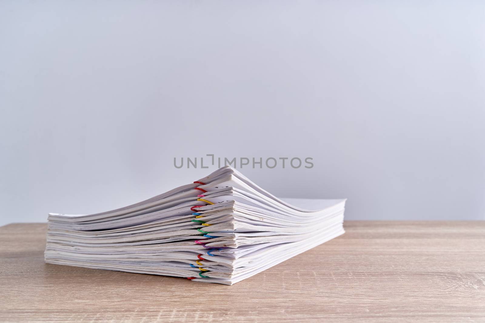 Pile paperwork of report with colorful paperclip place on wood table and white background with copy space. Business and finance concepts successful photography.