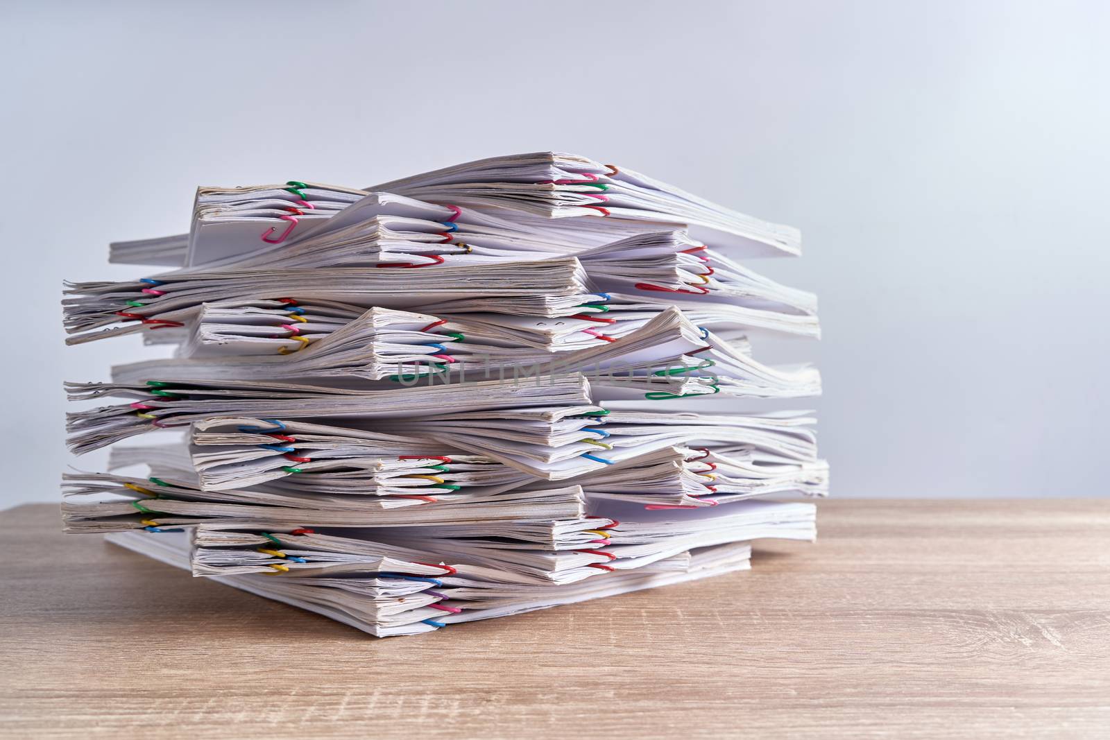 Pile overload document of report of sale and receipt with colorful paperclip place on wood table and white background with copy space. Business and finance concepts successful photography.