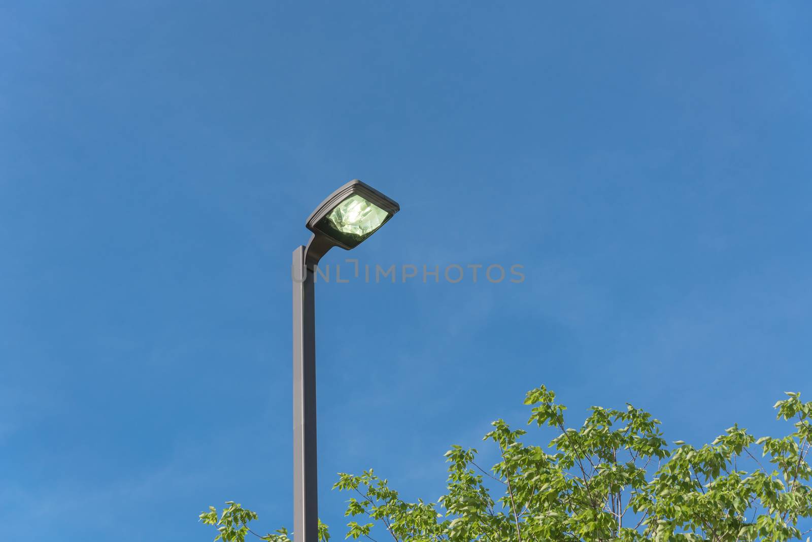 Bright street lamppost at daytime for wasting electricity concept by trongnguyen