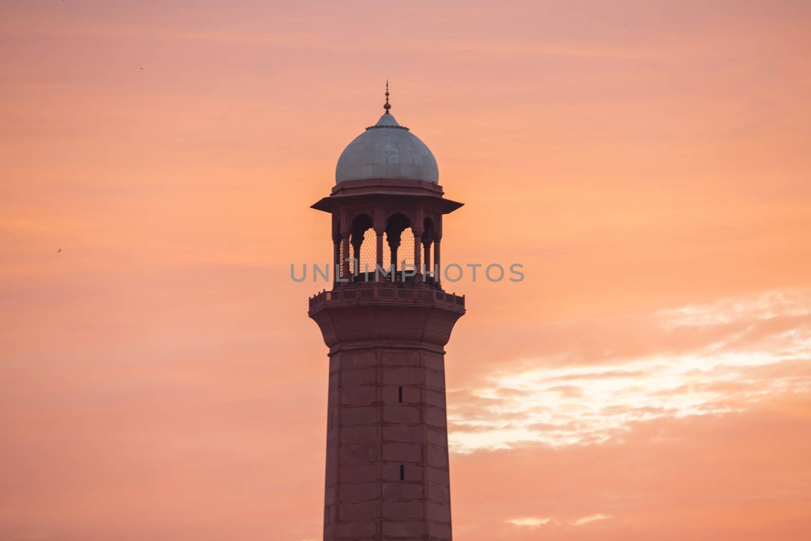 Minaret tower of a mosque calling for prayers in fiery sunset sky