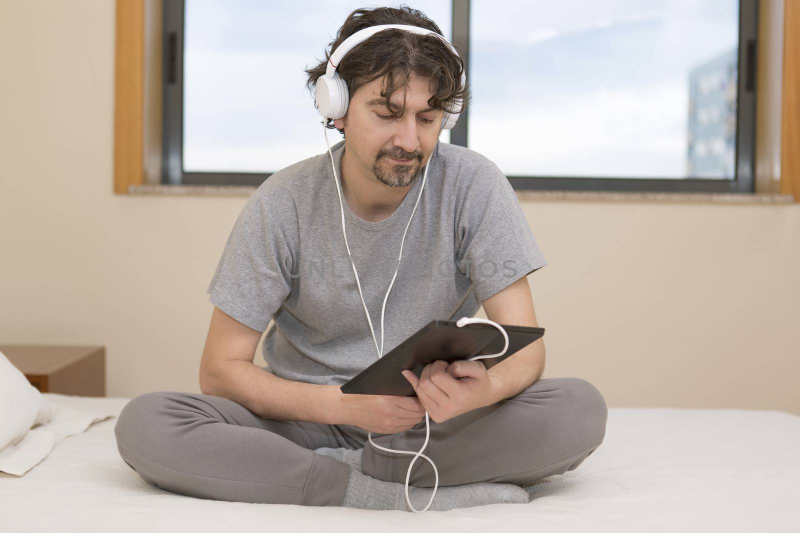 casual man working with a tablet pc in bed