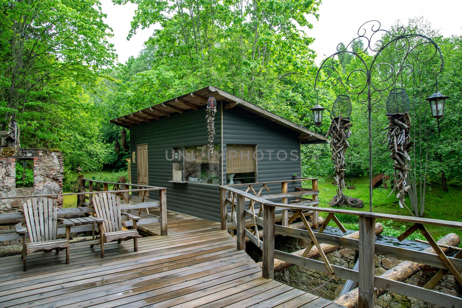 Wooden hut in the recreation camp with a bridge and chairs next to the forest.