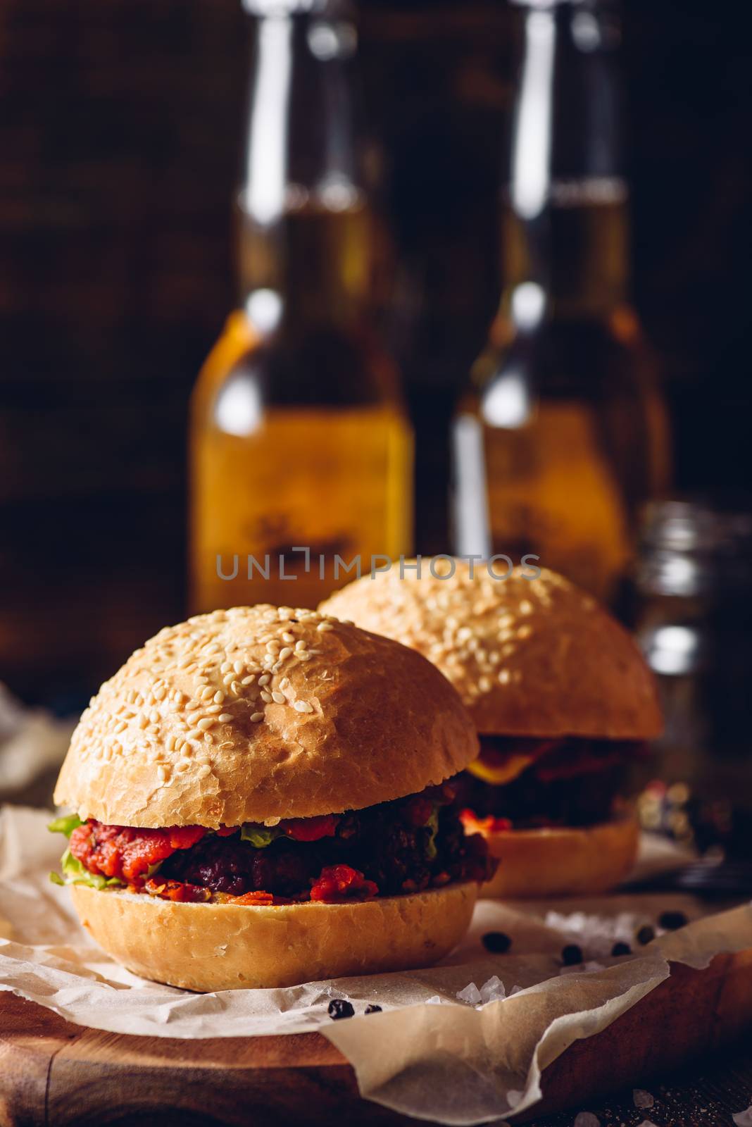 Two Cheeseburger on Cutting Board and Few Bottle of Beer on Background. Vertical Orientation.